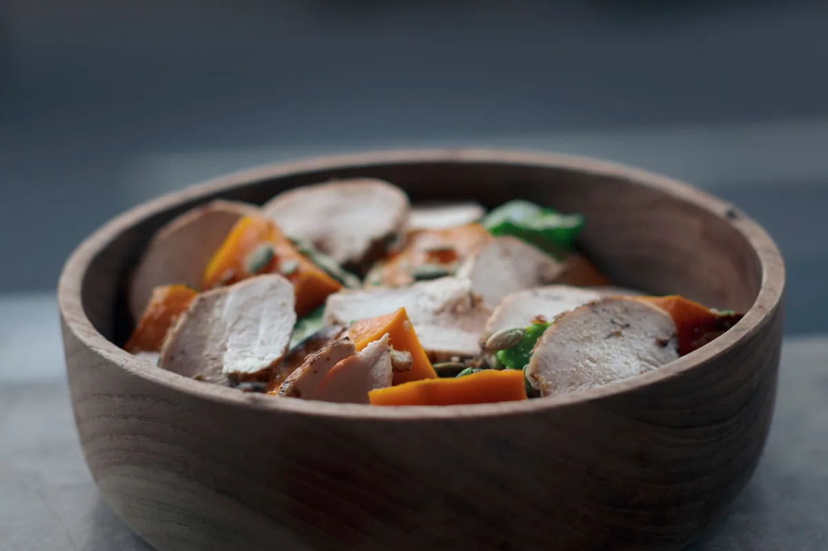 Flat bowl of boiled chicken and pumpkin puree on a kitchen counter, illustrating a bland pre‑travel meal for dogs