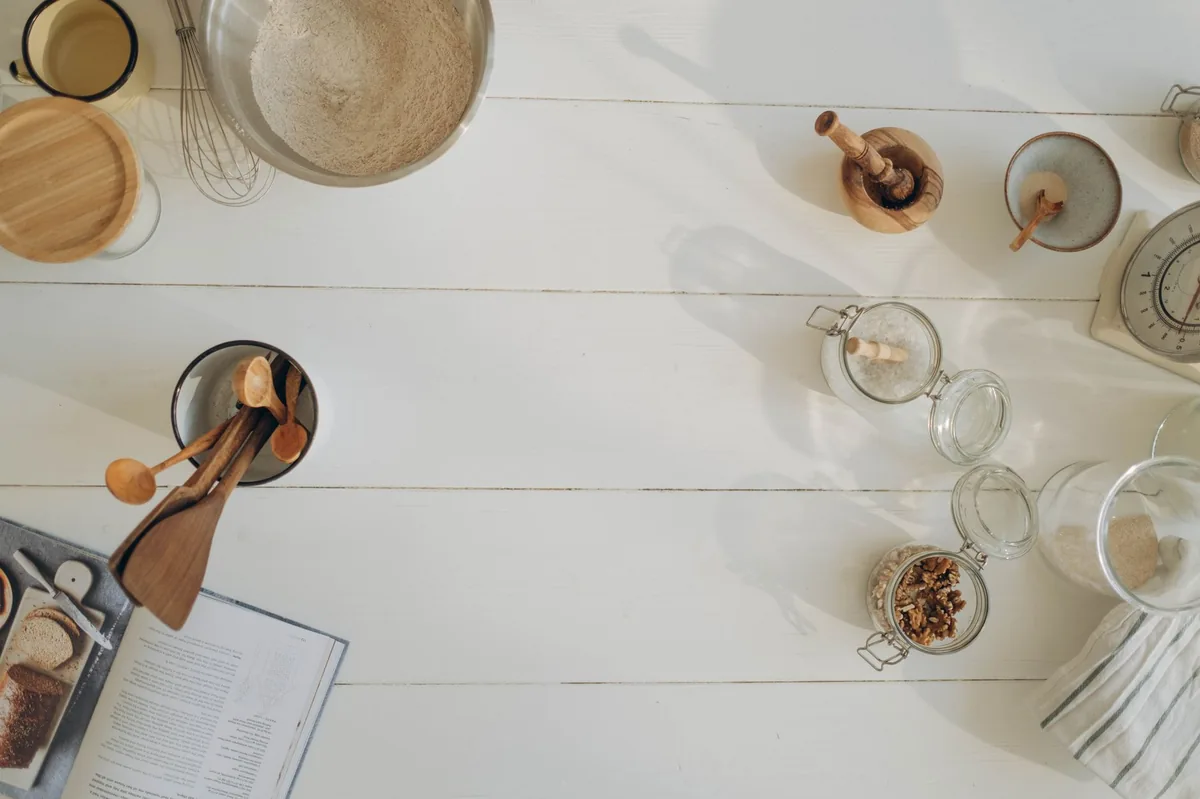 Dog food bowl with kibble and a spoonful of fish oil, placed on a wooden kitchen counter beside a glass of water