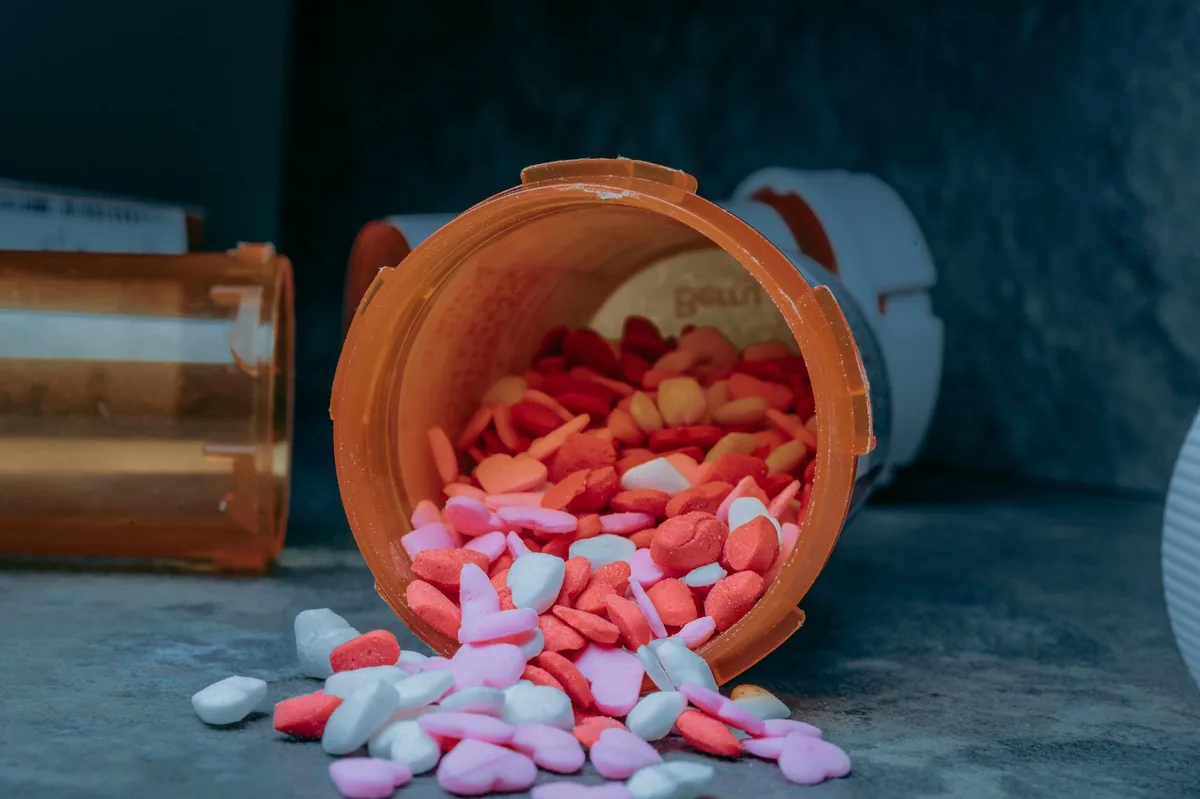 Close‑up of a dog food bowl with balanced kibble, a fish oil capsule, and a small glass of water on a kitchen counter