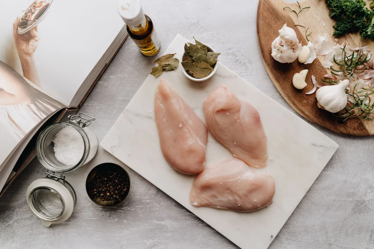 Fresh chicken breast, green beans, and a scoop of fish oil beside a bowl of low‑sodium therapeutic dog food